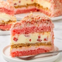 A slice of layered strawberry shortcake cheesecake.