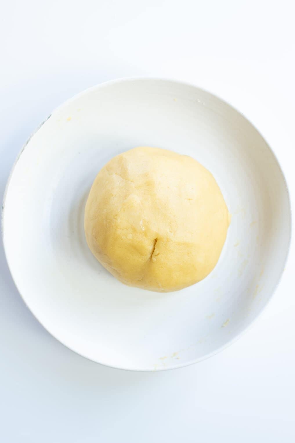 sugar cookie dough rolled into a large ball sitting on a white round plate.