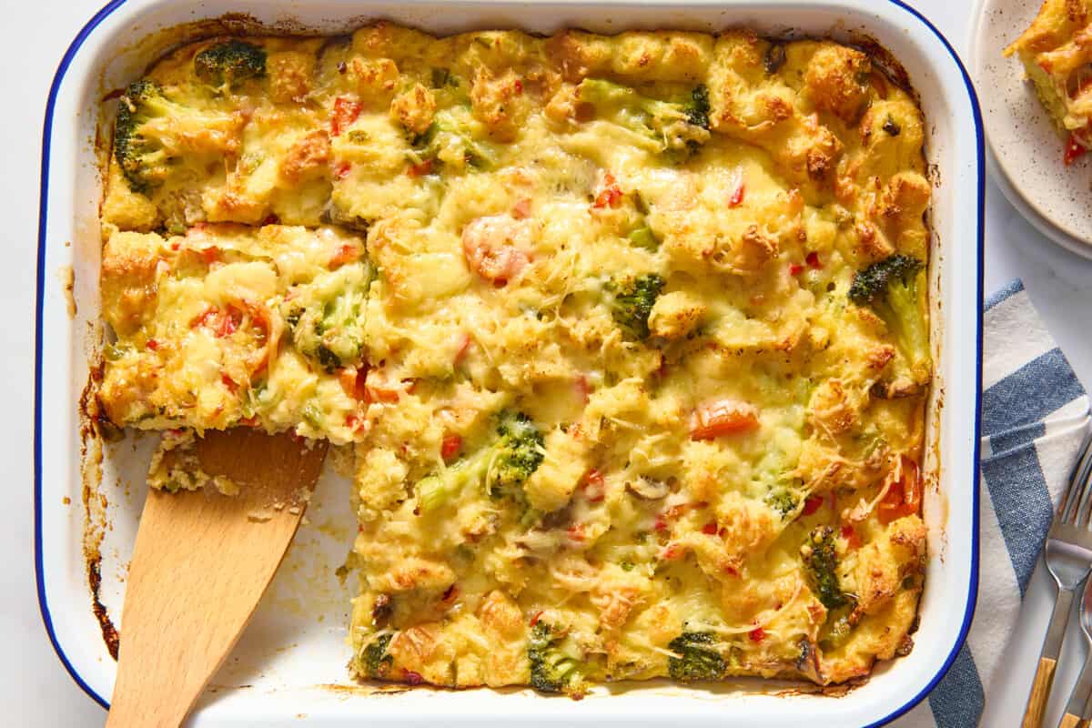 Vegetarian breakfast casserole with a wooden spoon lifting a slice. 