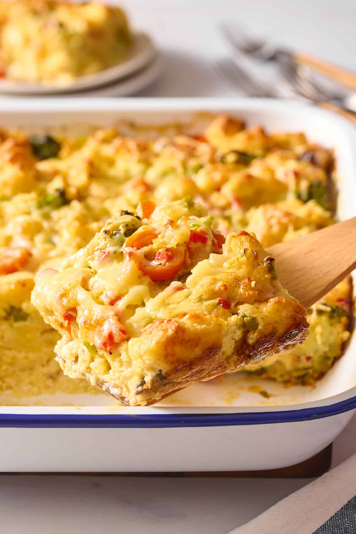 close up image of a wooden spatula digging into a serving of vegetarian breakfast casserole. 