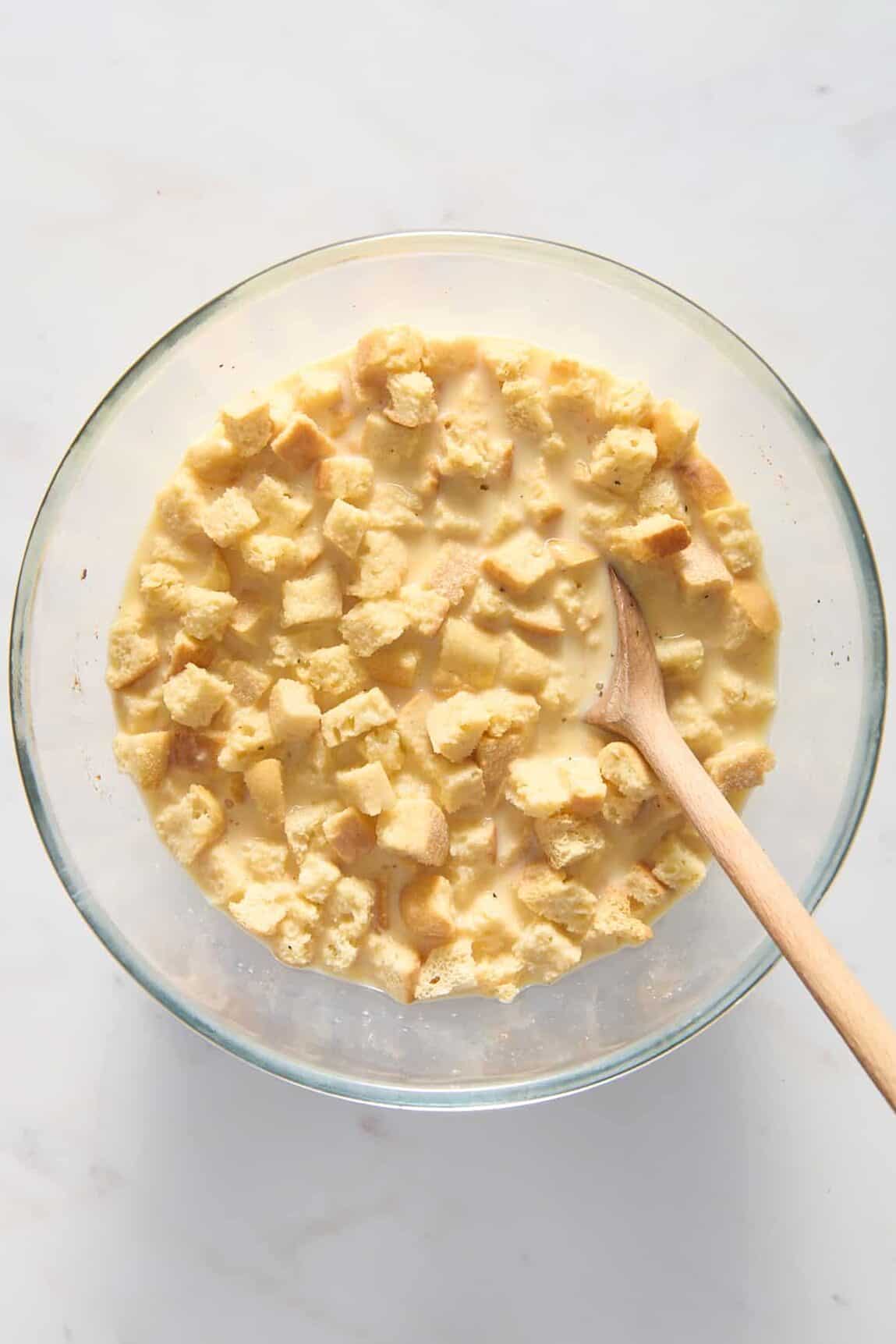 large glass bowl with cubed bread soaked in a egg and milk mixture. 