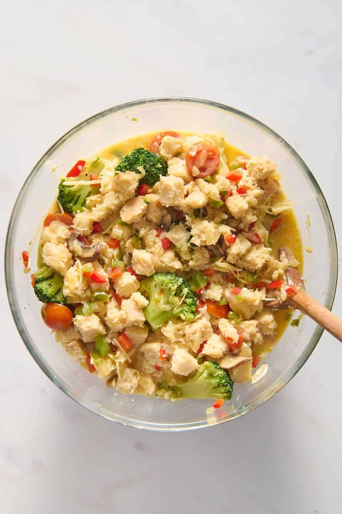 top down image of prepped vegetarian breakfast casserole ingredients sitting in a large glass bowl. 