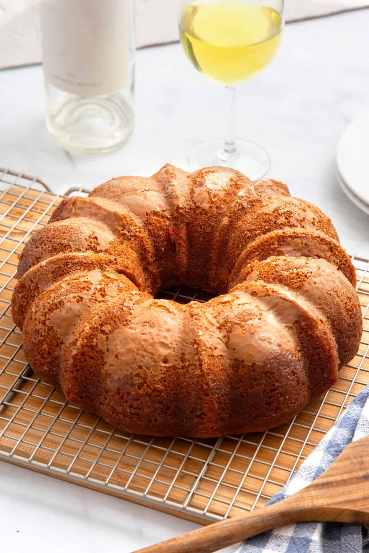 crack cake in a bundt shape sitting on a wire cooling rack on top of a wood cutting board. 
