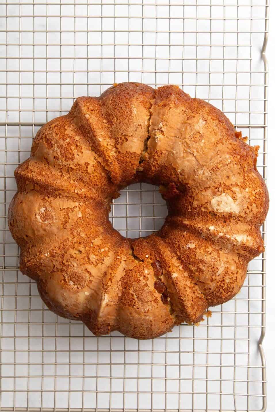 top down image of crack bundt cake cooling on a wire rack. 