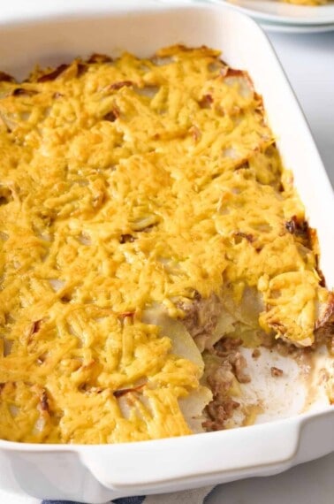 Hamburger and potato casserole in a baking dish with a serving missing.