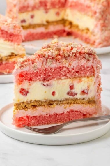 A slice of layered strawberry shortcake cheesecake.