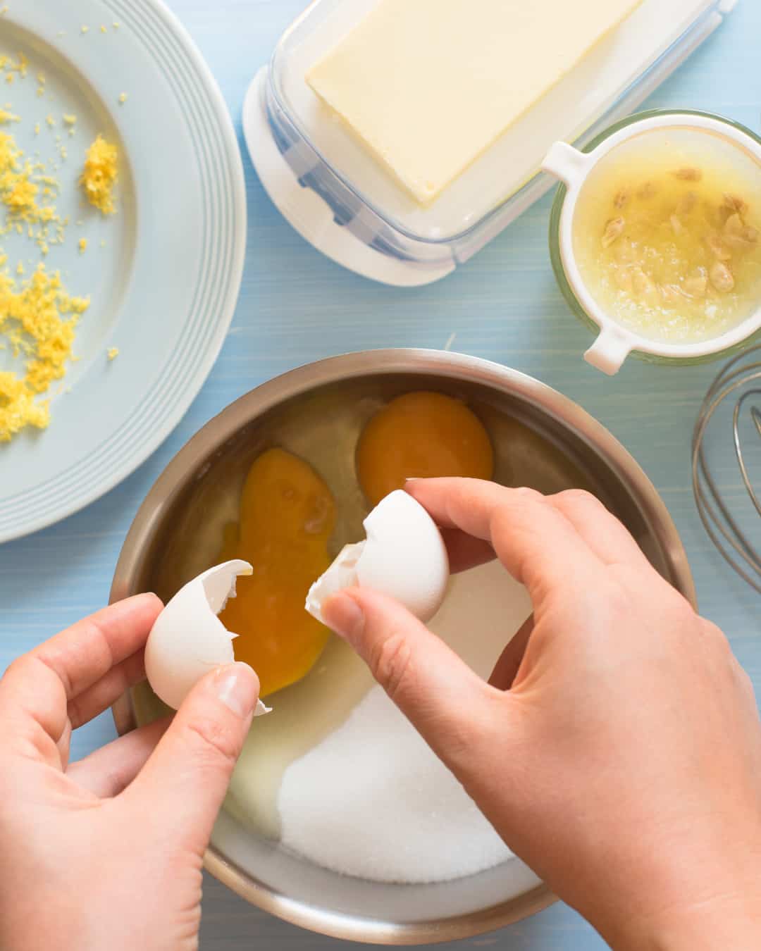 cracking an egg into a sauce pan with granulated sugar. 