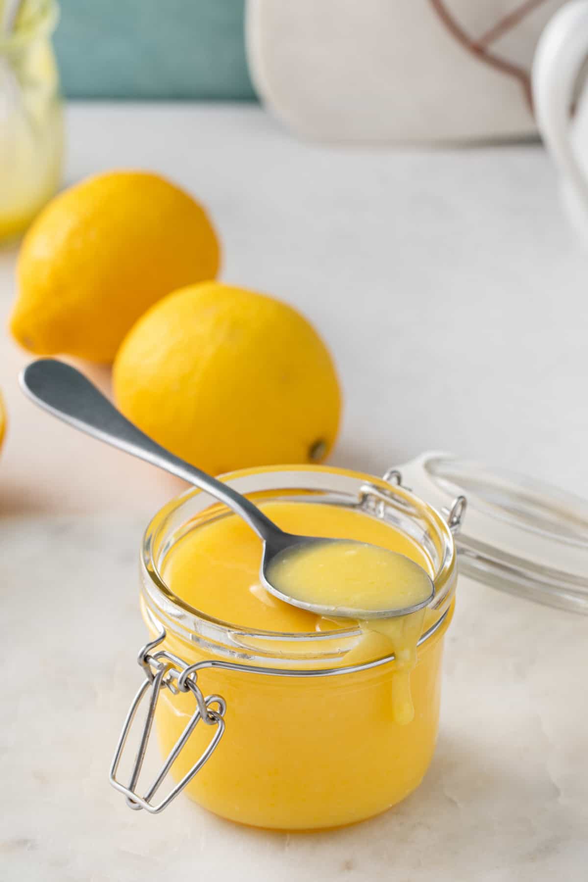 glass jar with homemade lemon curd and a silver spoon. 
