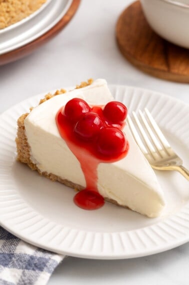 A slice of Philadelphia no-bake cheesecake topped with cherries on a plate.