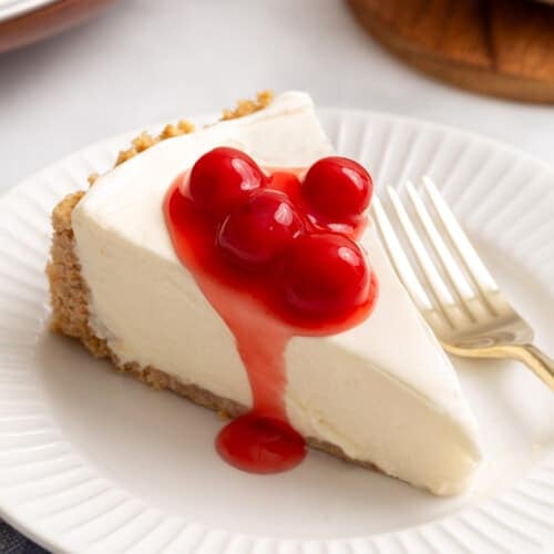 A slice of Philadelphia no-bake cheesecake topped with cherries on a plate.