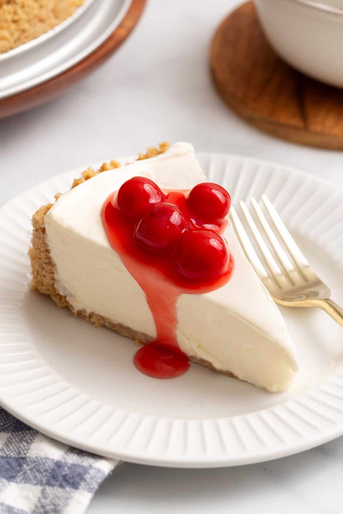 close up image of a slice of Philadelphia No Bake Cheesecake served on a white round plate.