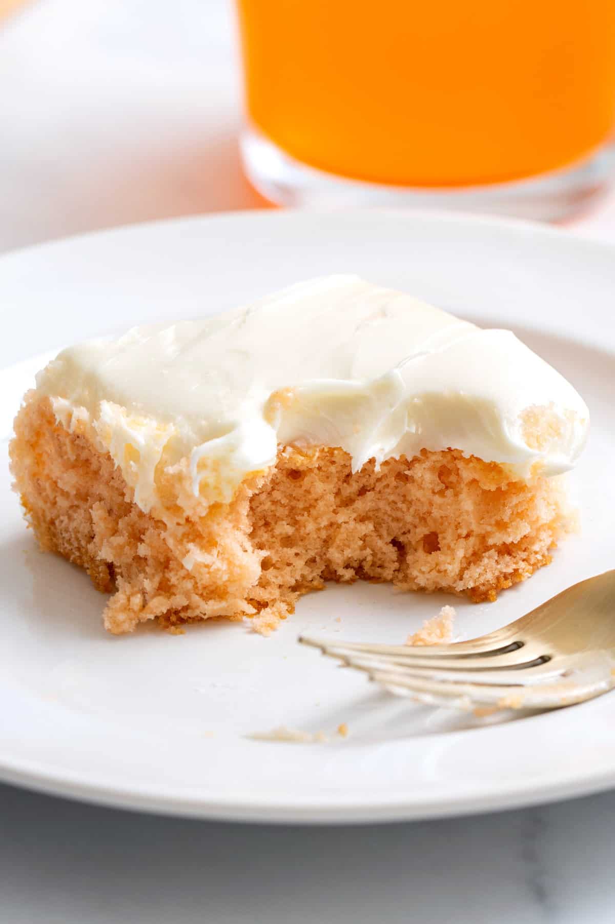 close up image of a square slice of soda cake frosted sitting on a white round plate. 