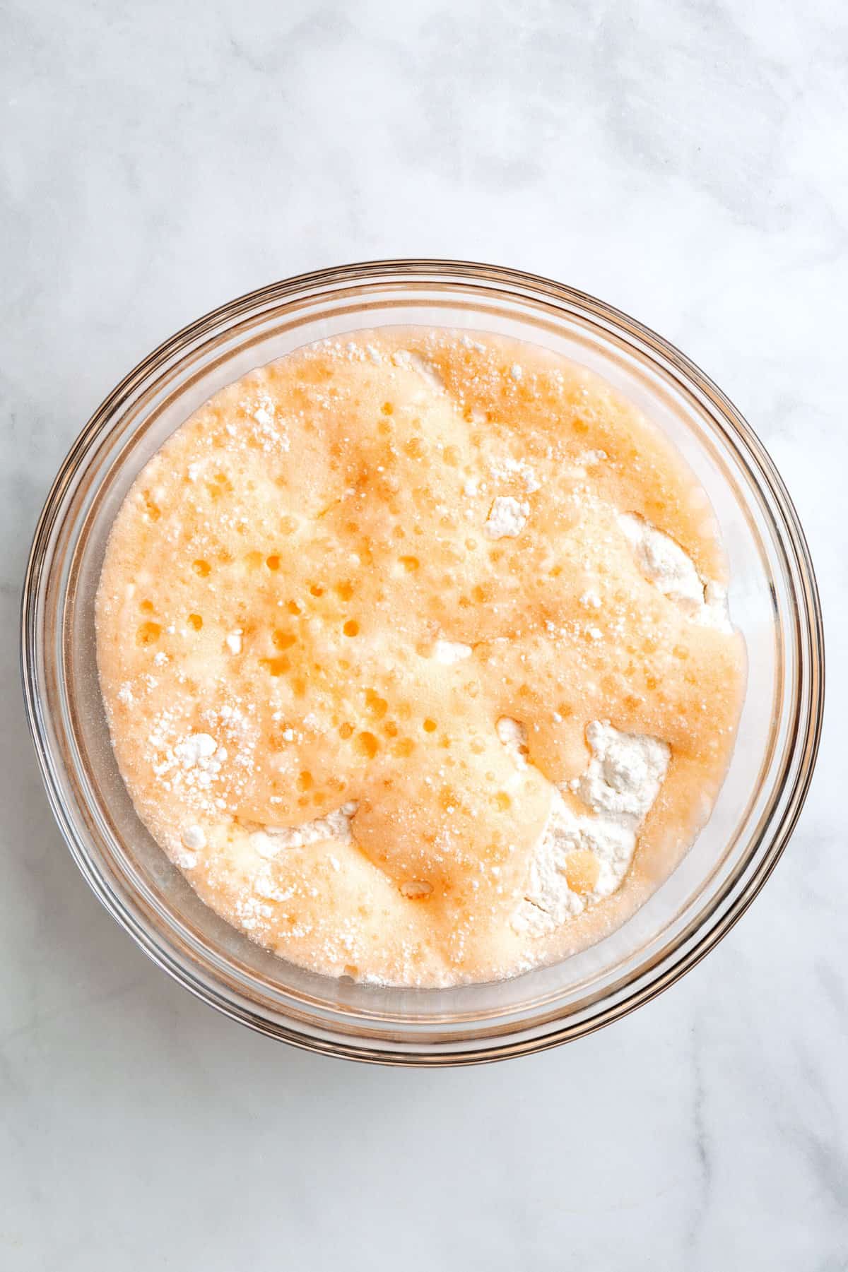 top down image of orange soda and cake mix in a large glass bowl. 