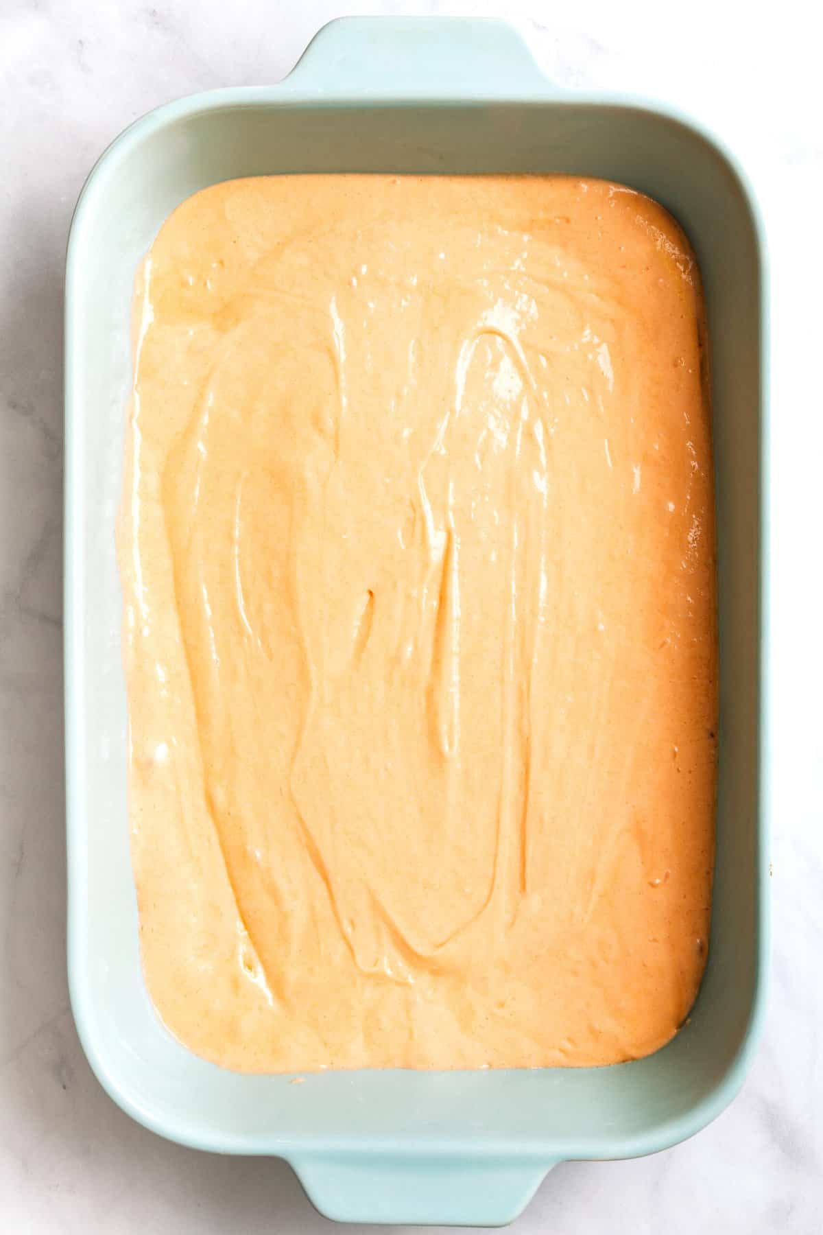 top down image of soda cake batter sitting in a 9x13 casserole baking dish. 