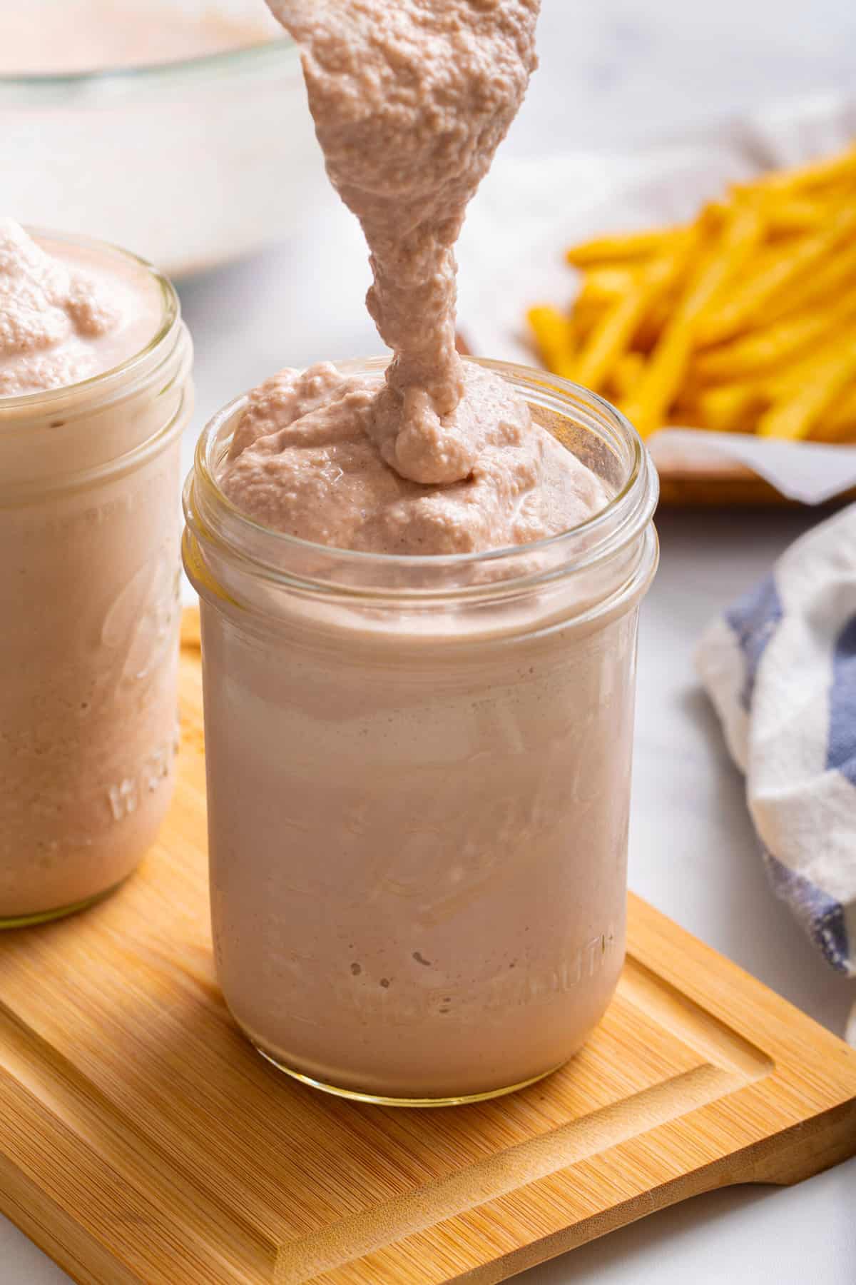 close up image of a mason jar of a homemade wendy's frosty with a silver spoon and sitting on a wood cutting board. 