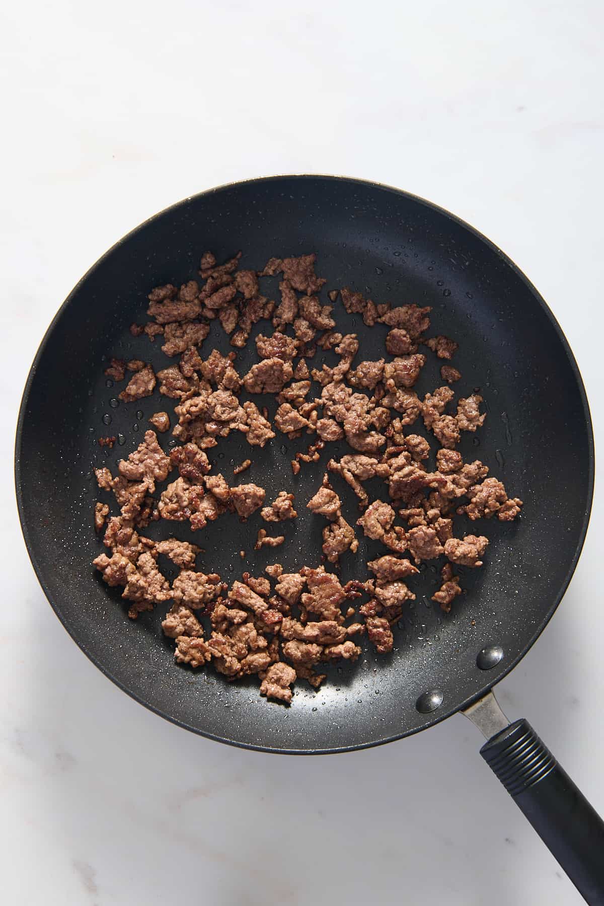 top down image of ground beef cooking in a large skillet.
