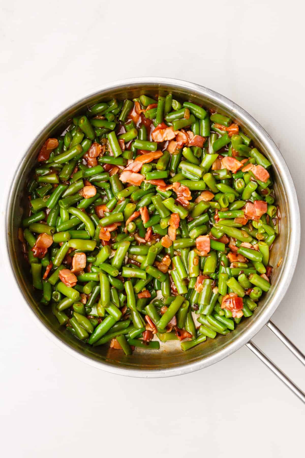 top down image of crack green beans sitting in a large skillet. 
