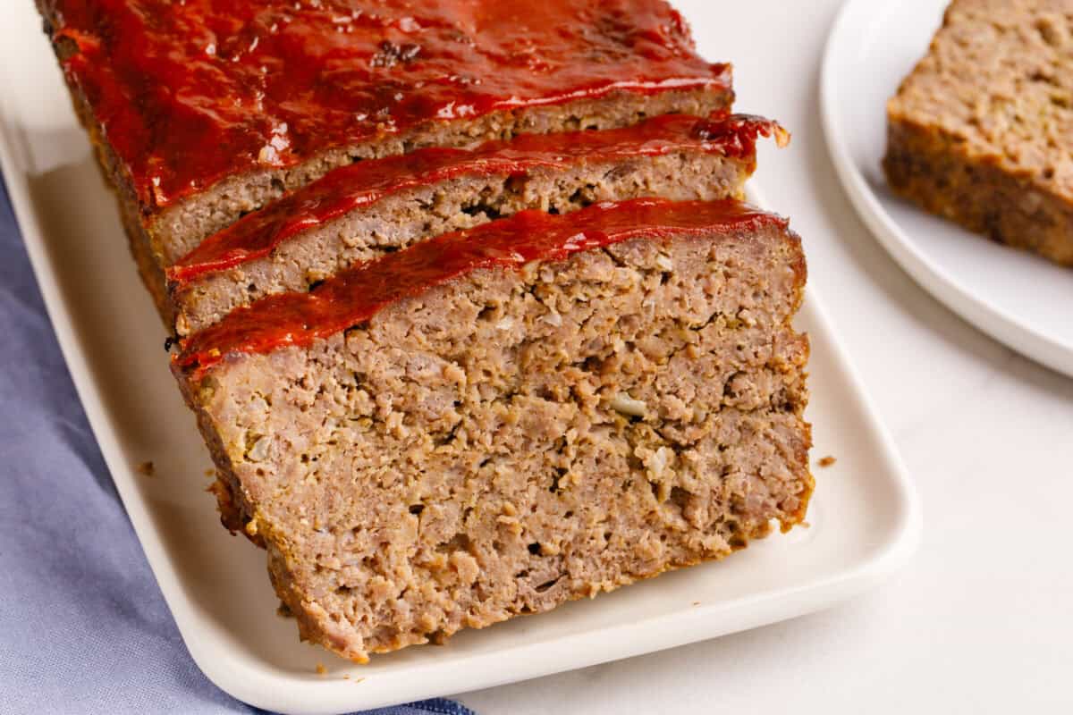 Cracker Barrel meatloaf sliced and resting on a wooden cutting board, showing the juicy texture of the meat