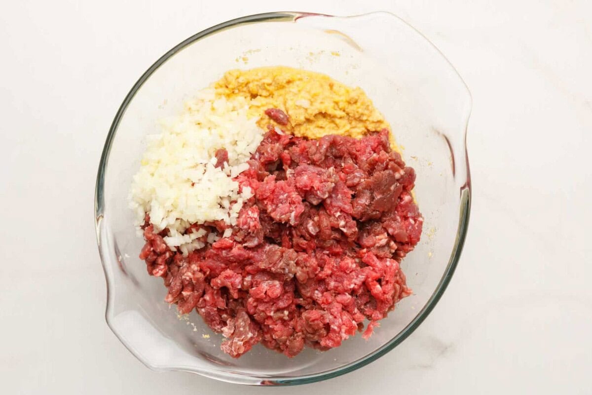 Ground beef mixture with breadcrumbs, eggs, and spices in a large mixing bowl for Cracker Barrel meatloaf preparation