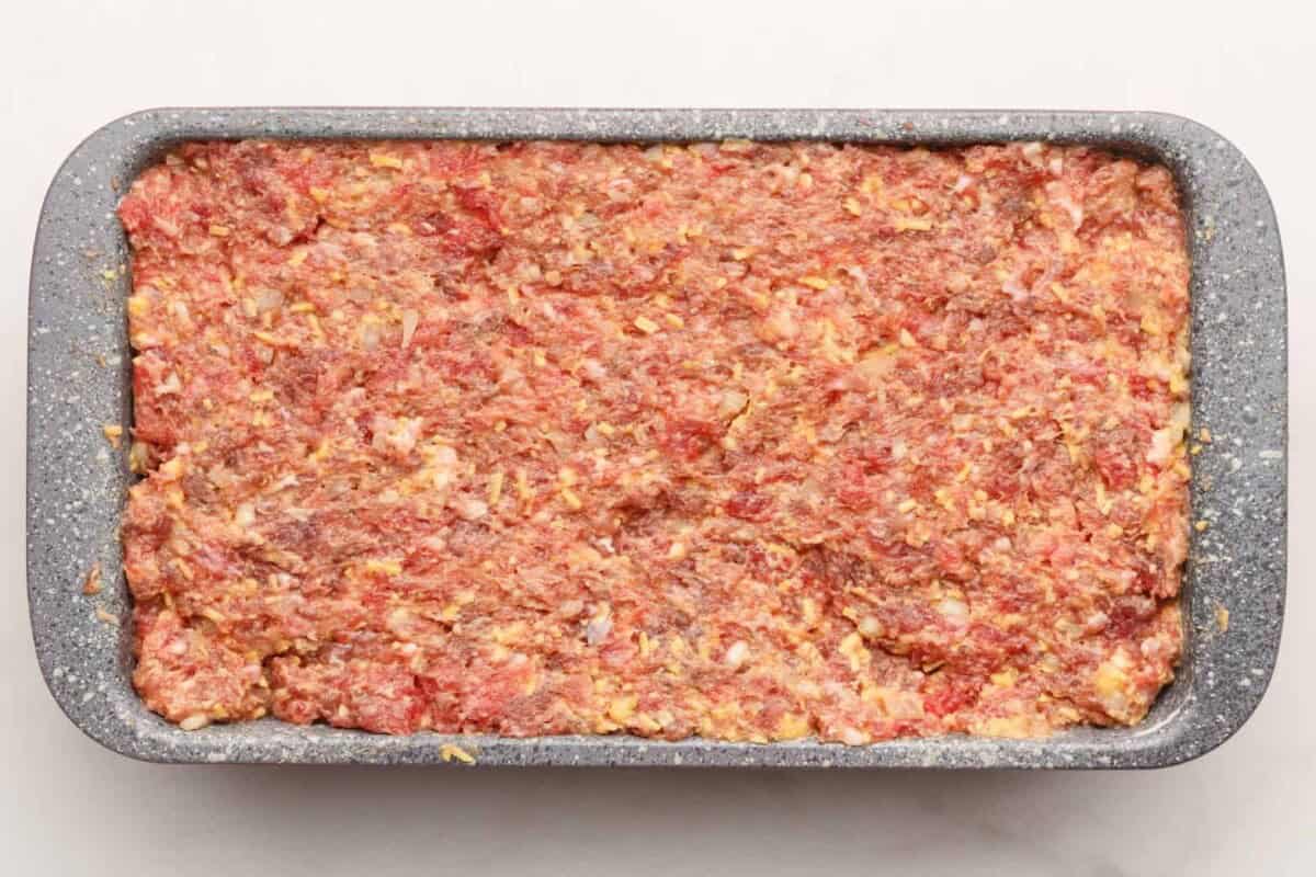 Cracker Barrel meatloaf mixture pressed into a loaf pan before baking, ready to go into the oven