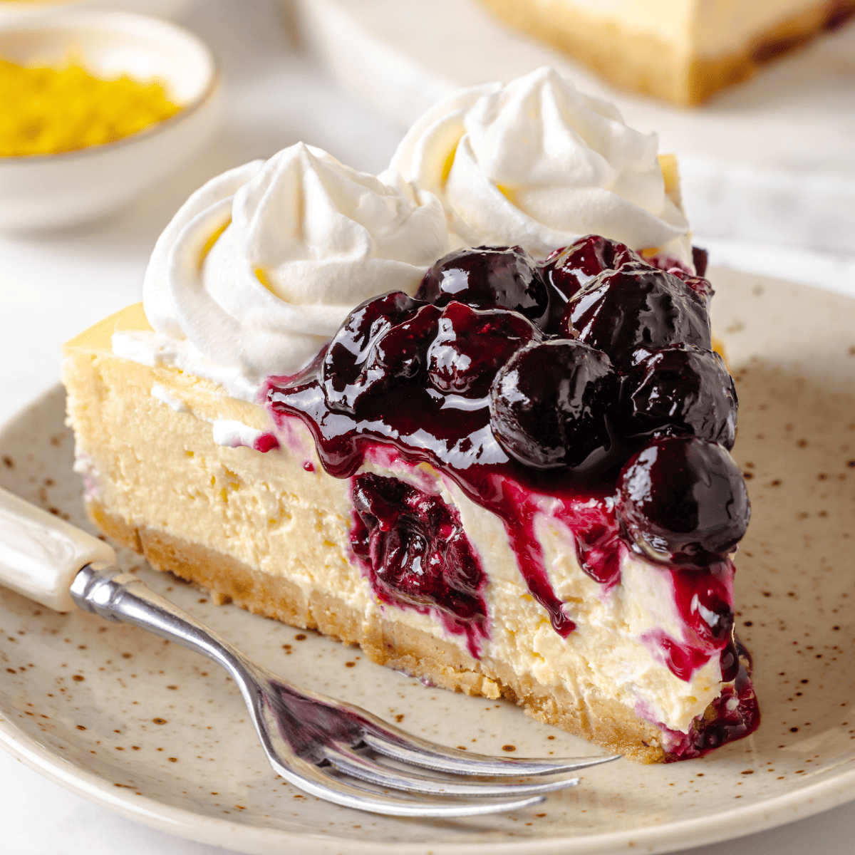 A slice of lemon blueberry cheesecake on a plate.