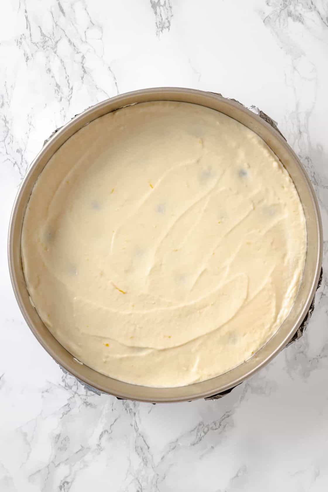 top down image of homemade Lemon Blueberry Cheesecake prepped to bake sitting in a springform pan. 