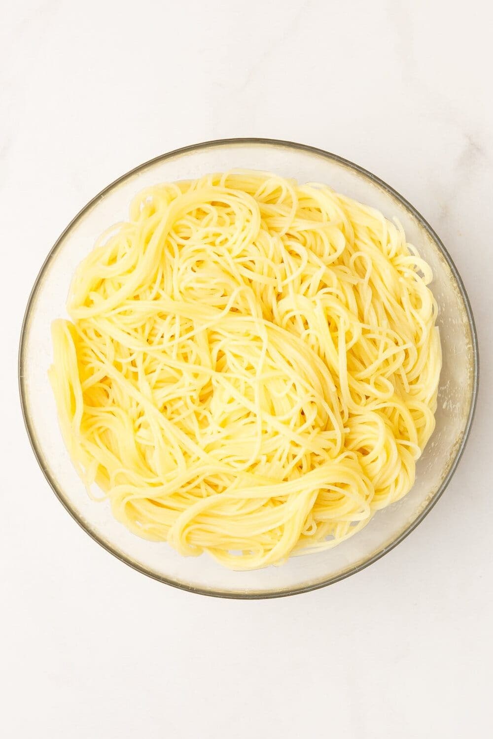 large glass bowl with cooked angel hair pasta. 