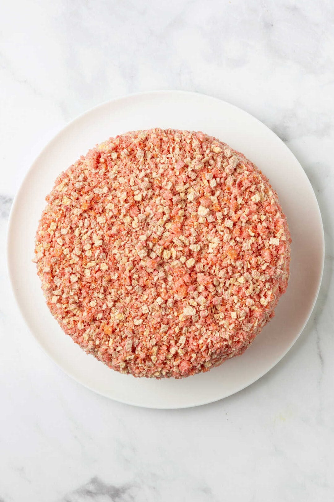 top down image of strawberry shortcake cheesecake sitting on a white round cake plate.