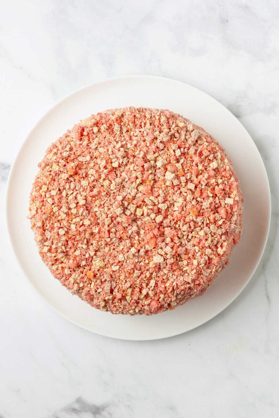 top down image of strawberry shortcake cheesecake sitting on a white round cake plate. 