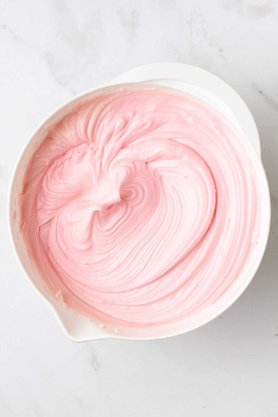 large white mixing bowl with strawberry frosting. 