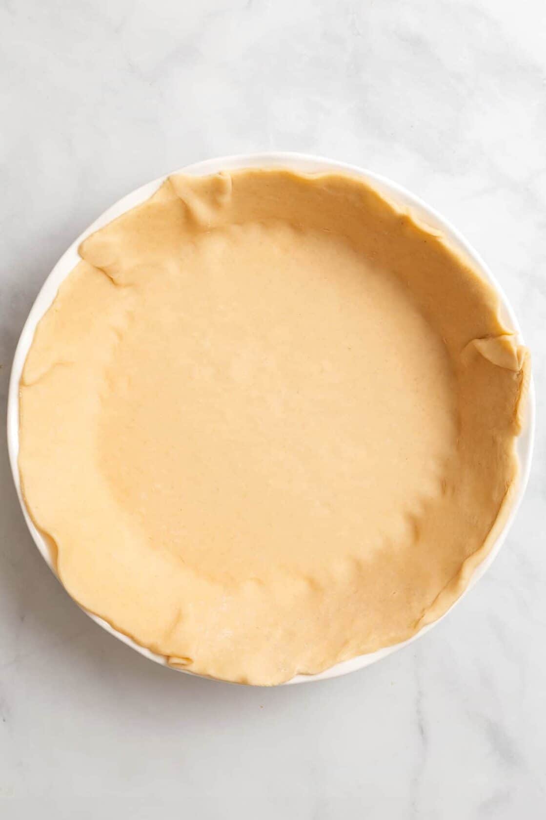 top down image of raw pie crust lined on a pie dish. 