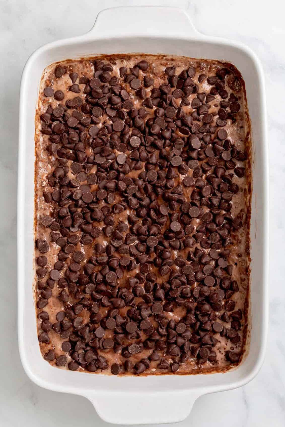 top down image of unbaked chocolate dump cake served in a 9x13 ceramic baking dish. 