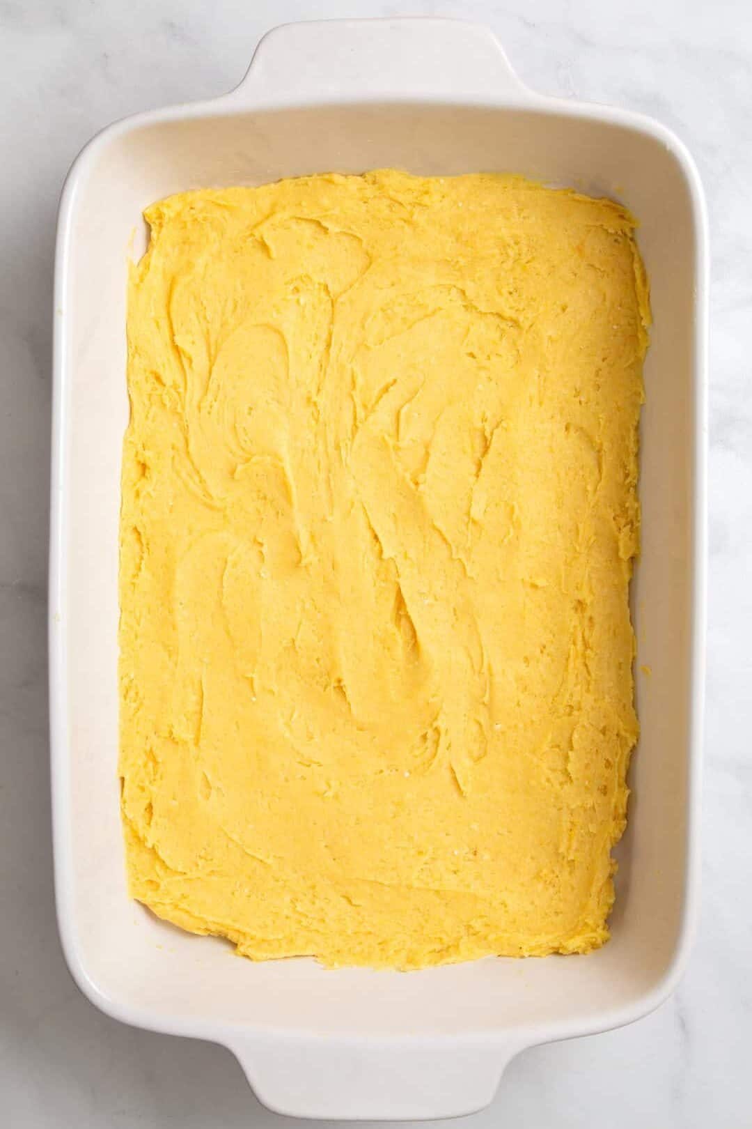 top down image of a 9x13 casserole dish with cake mix batter.