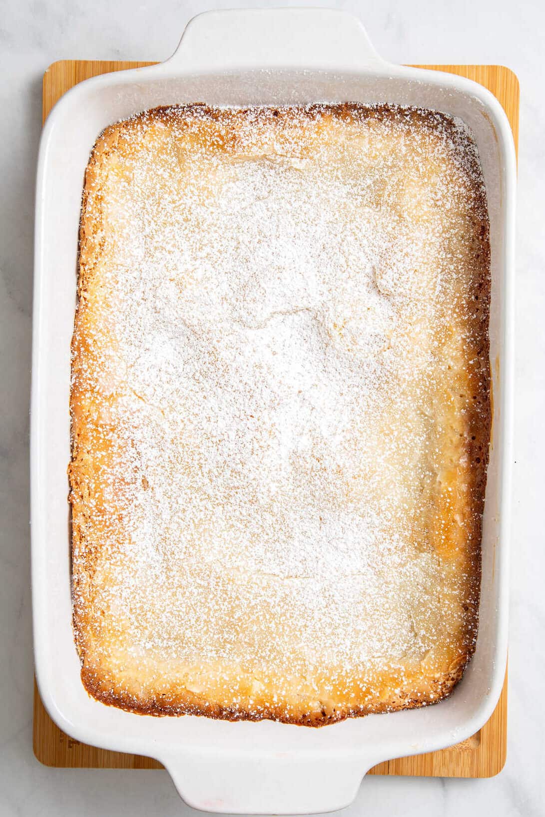 top down image of a 9x13 casserole dish with bake cake box mix topped with powdered sugar. 