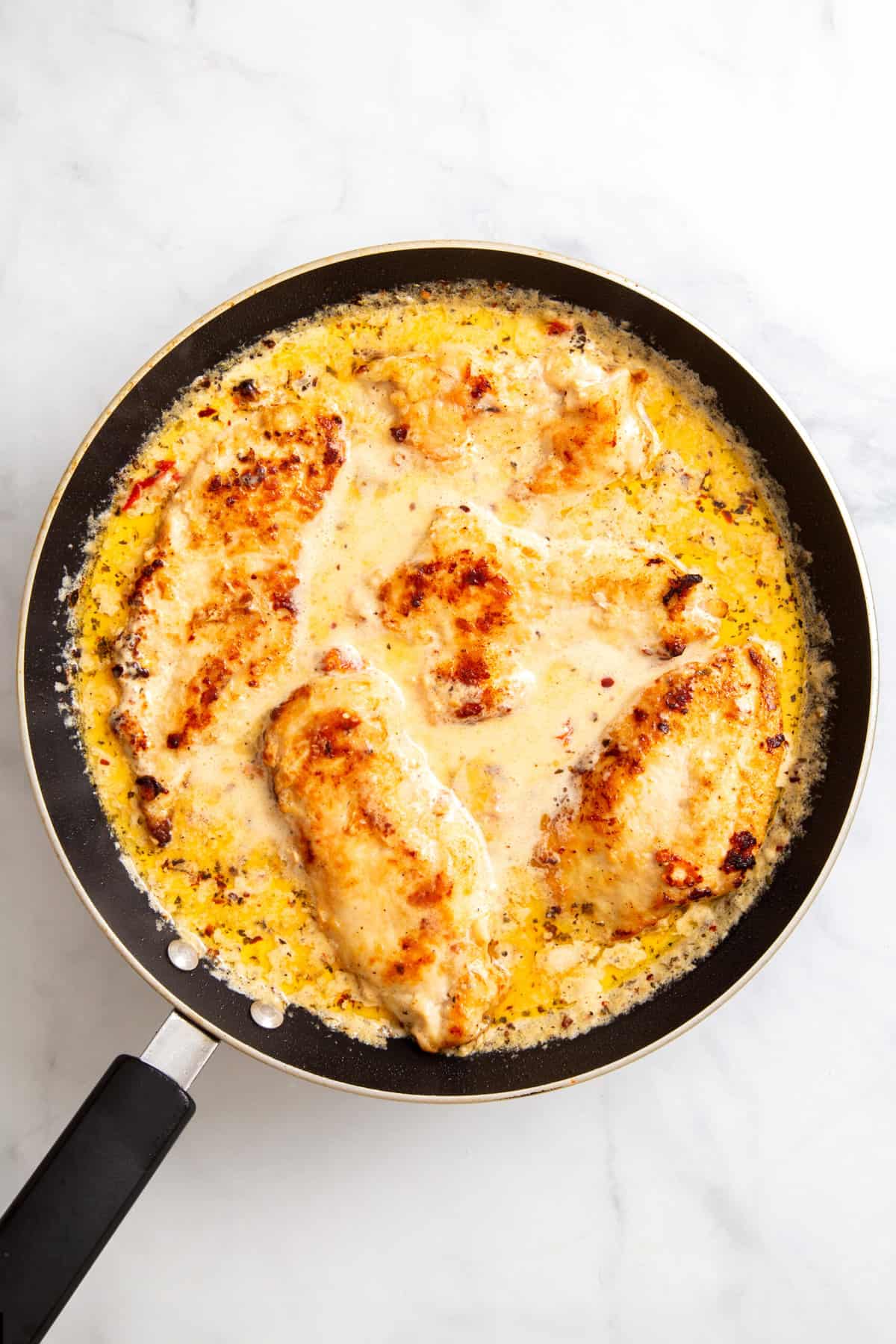 top down image of a skillet with marry me chicken sitting in sauce.