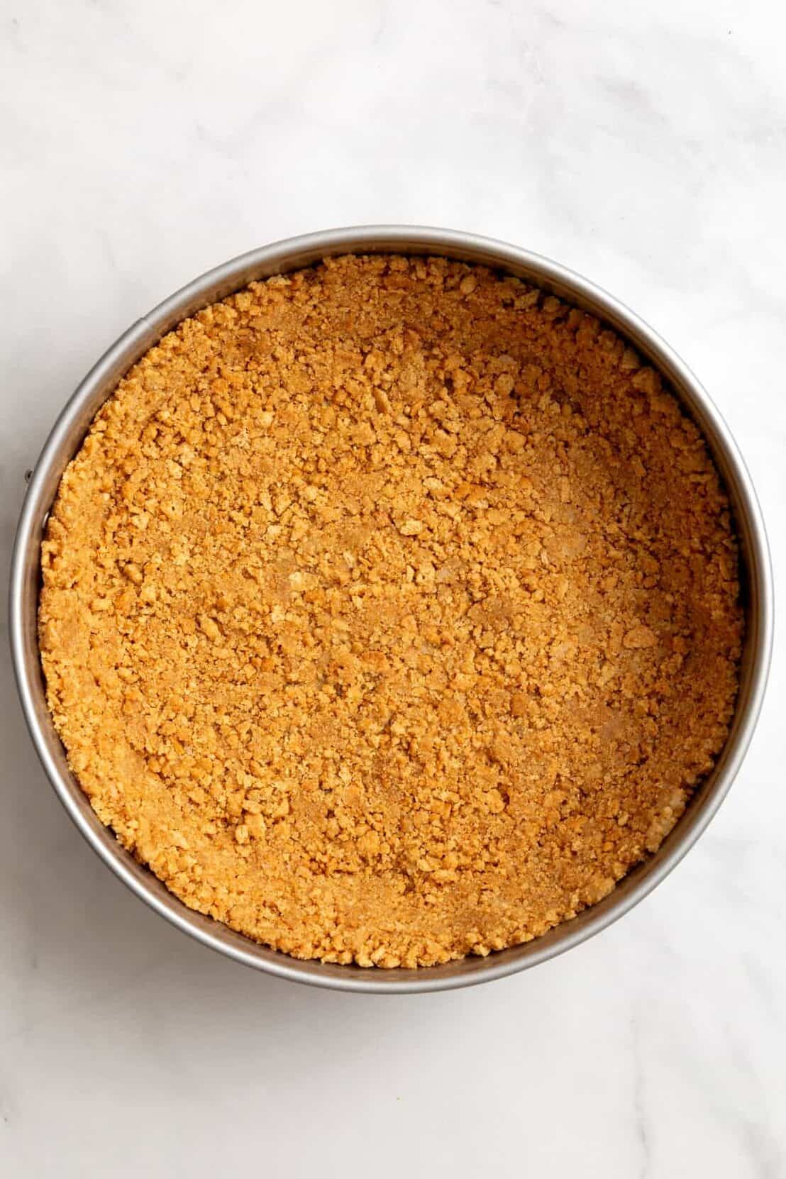 top down image of graham cracker crust pressed in a spring form pan. 