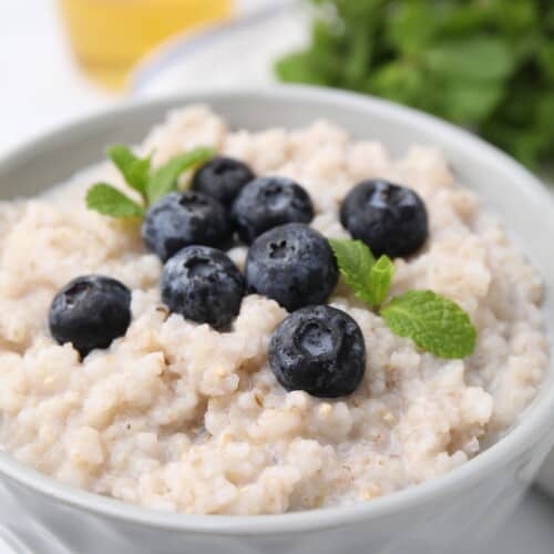 A bowl of oatmeal topped with blueberries.