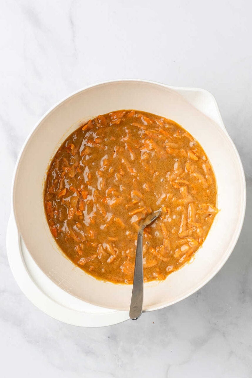 top down image of a white mixing bowl with carrot cake muffin batter.