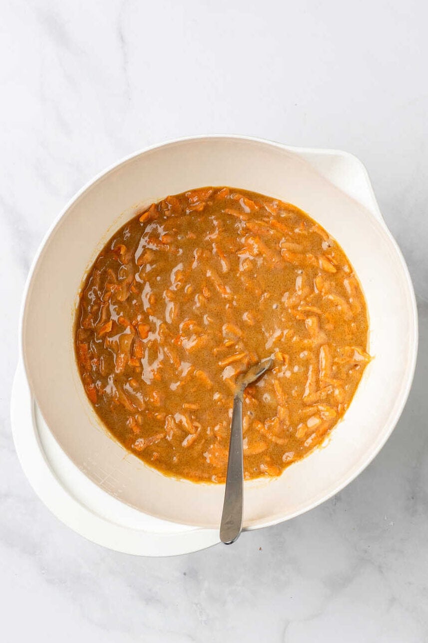 top down image of a white mixing bowl with carrot cake muffin batter. 