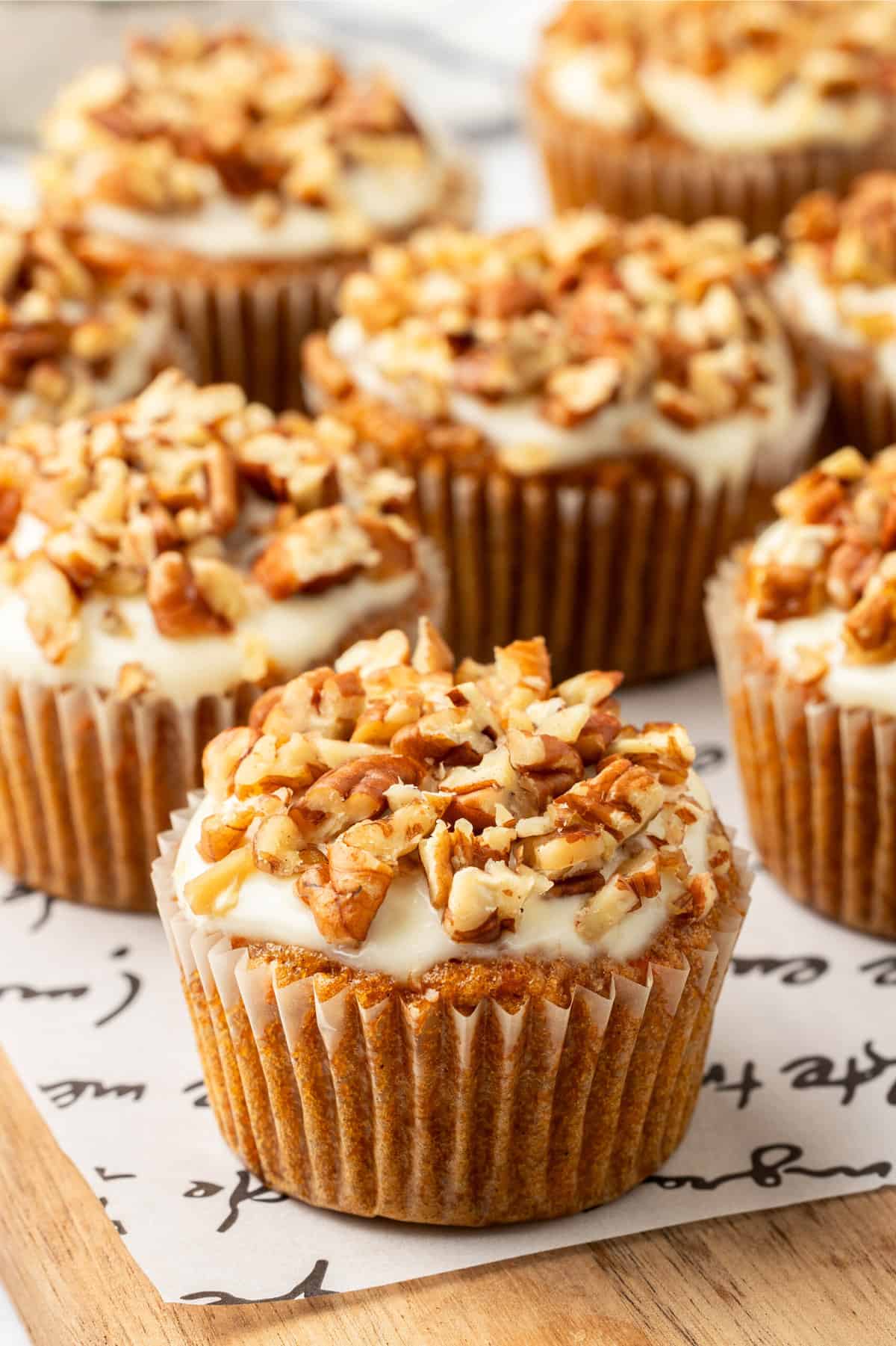 close up image of baked and decorated carrot cake muffins with cream cheese frosting.