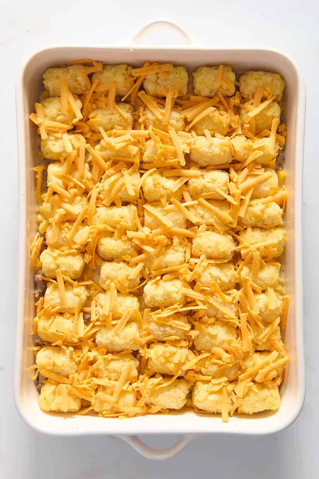 top down image of cowboy casserole prepped ready to bake sitting in a 9x13 inch casserole dish. 