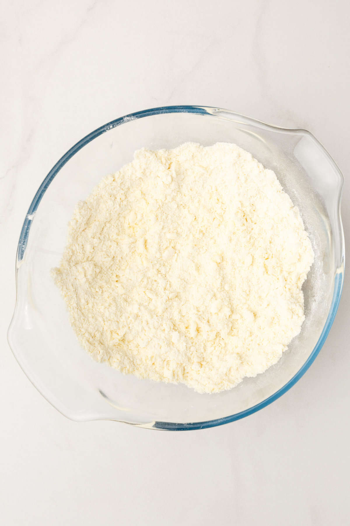 Top down image of a large glass mixing bowl with flour.