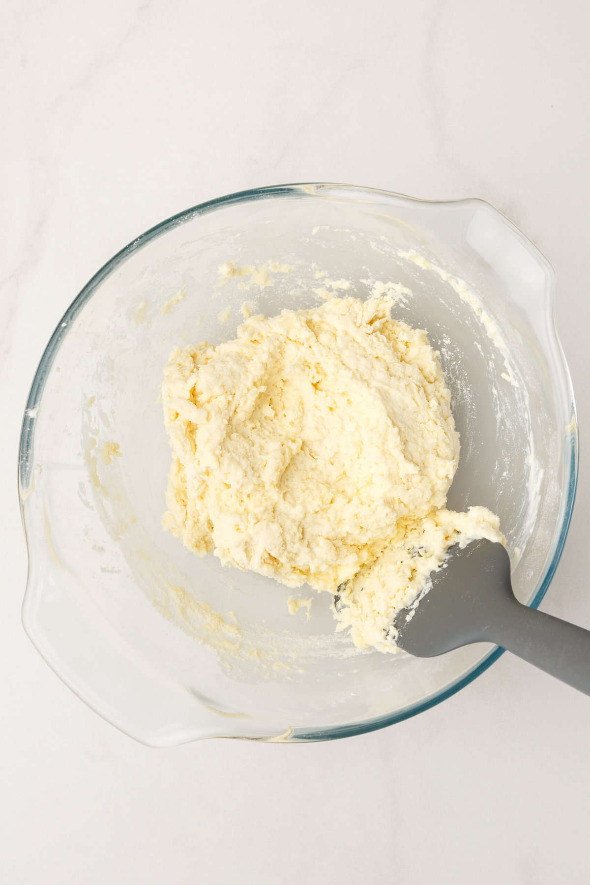 Top down image of homemade Popeyes biscuit dough, sitting in a large glass mixing bowl.
