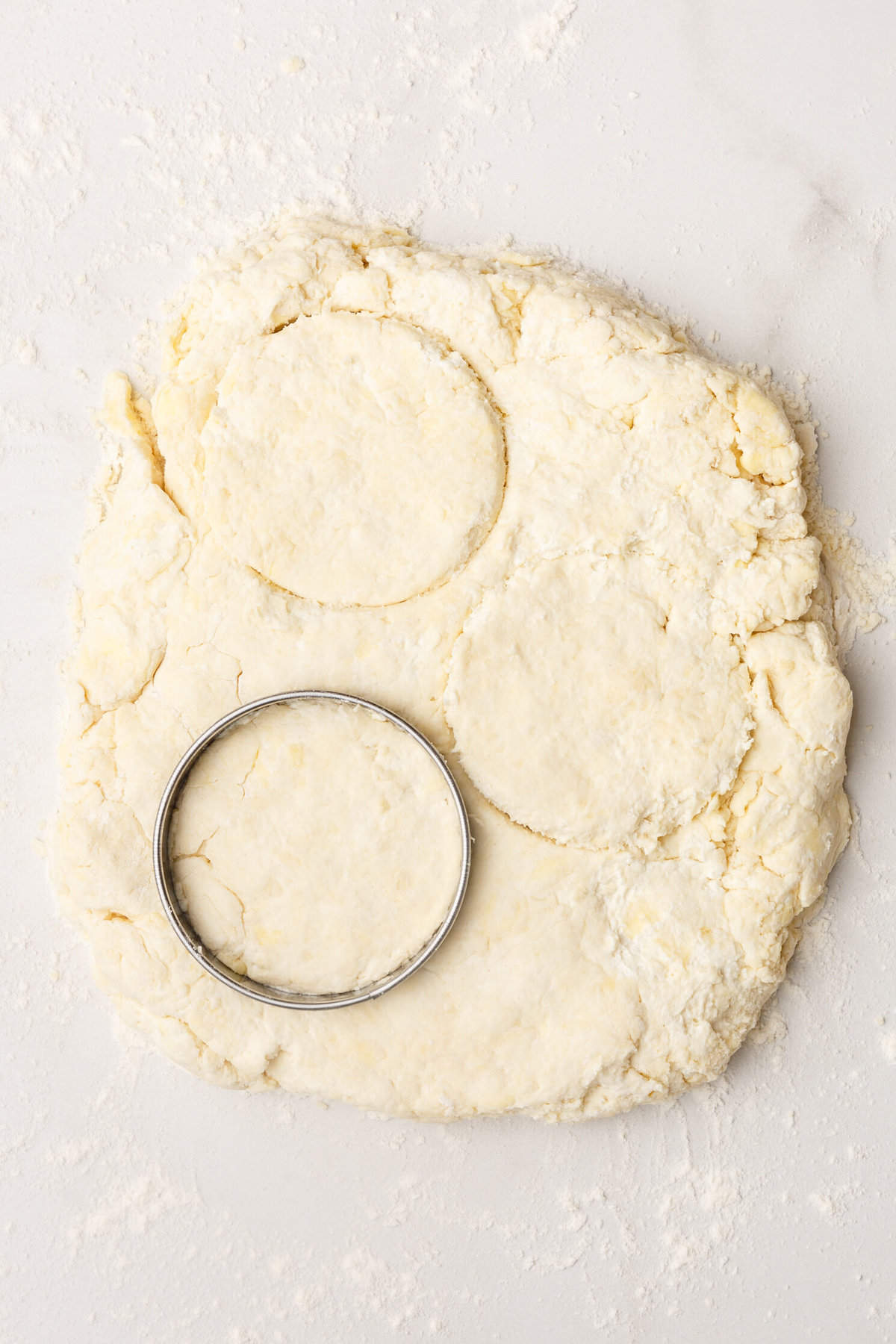 top down image of homemade Popeyes biscuit dough being cut with a circle cookie cutter.