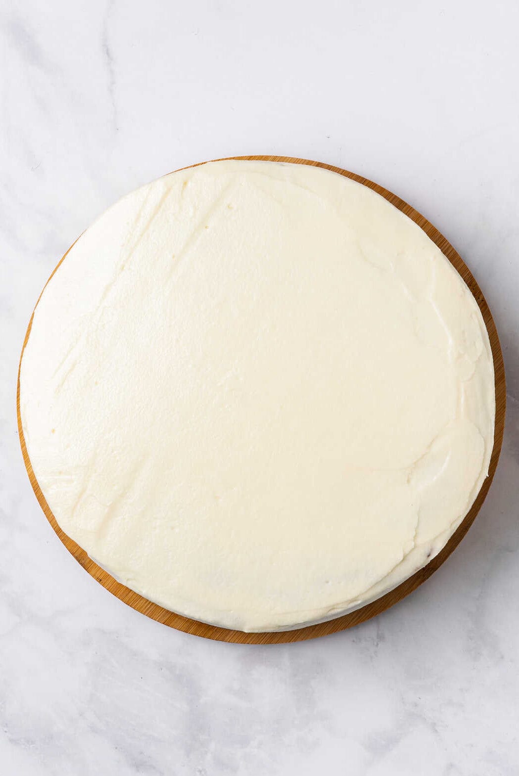 top down image of a stacked and frosting carrot cake. 