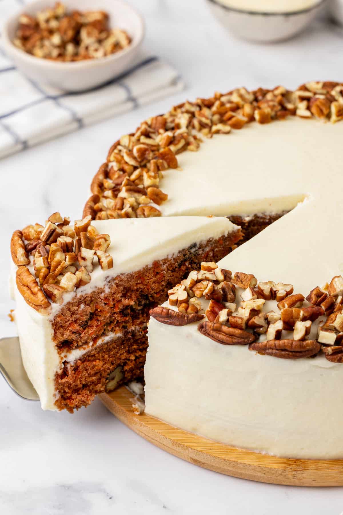 close up image of a cake spatula taking a slice of simple carrot cake out of the whole cake. 