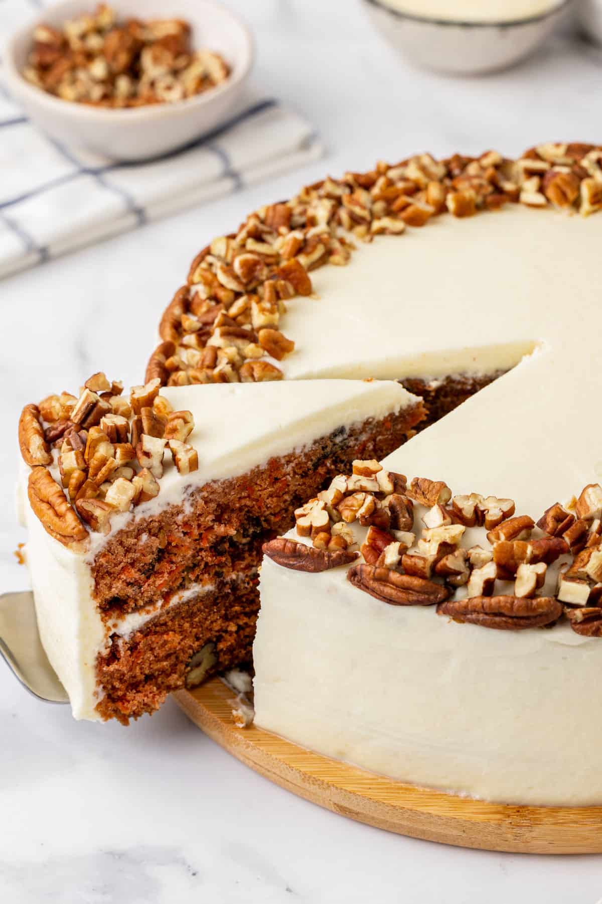 close up image of a cake spatula taking a slice of simple carrot cake out of the whole cake.