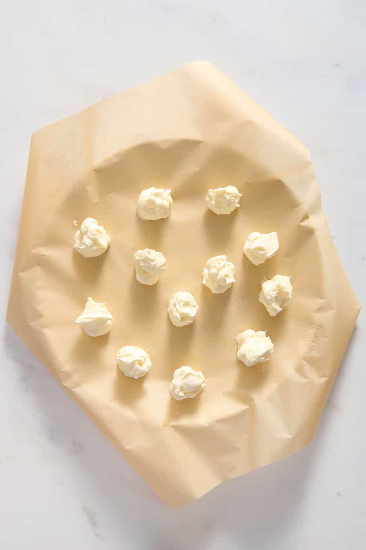 top down image of cheesecake filling balls prepared on a parchment-lined round baking tray. 