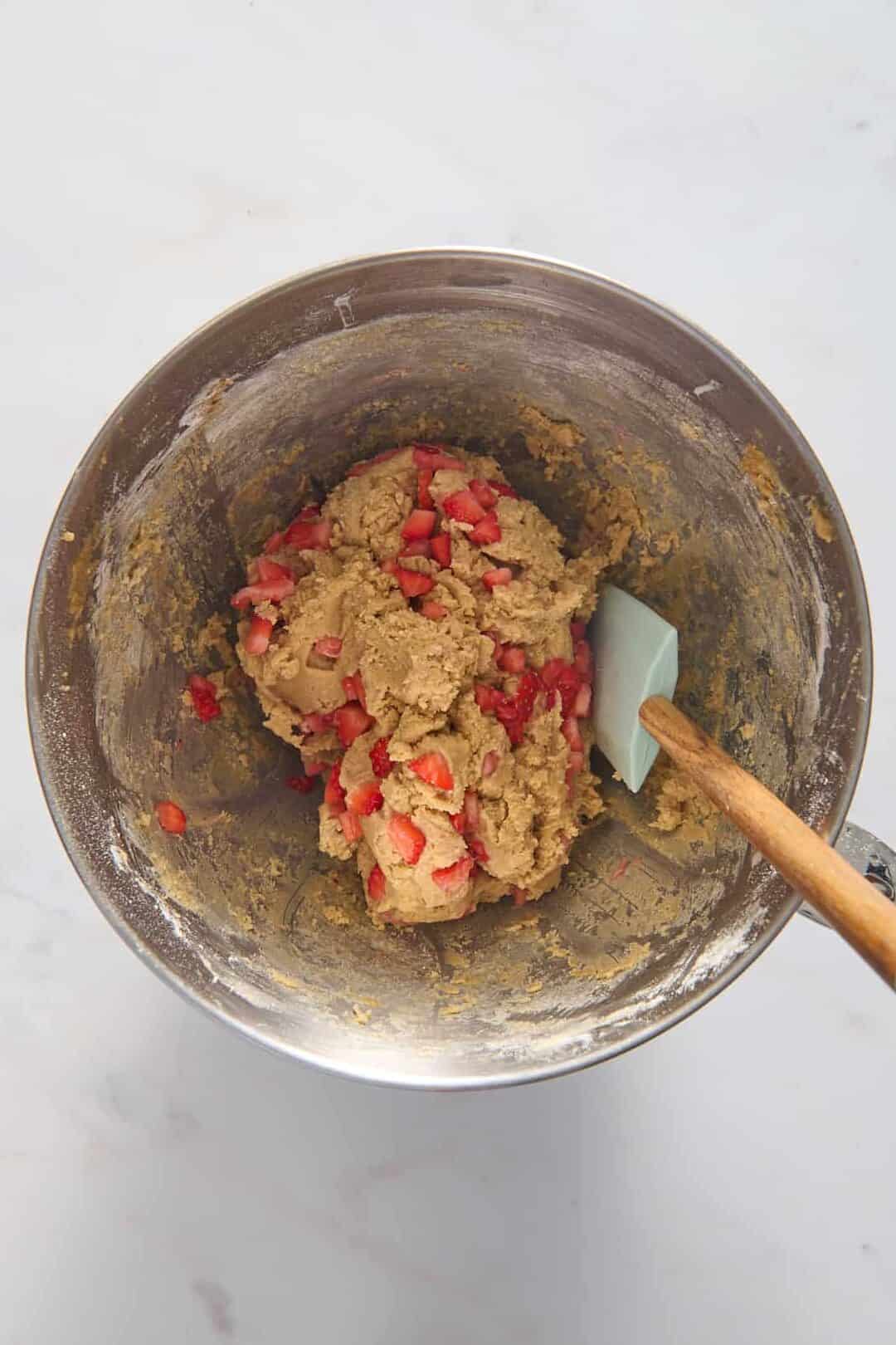 top down image of strawberry cheesecake cookie dough in a stainless steel mixing bowl.