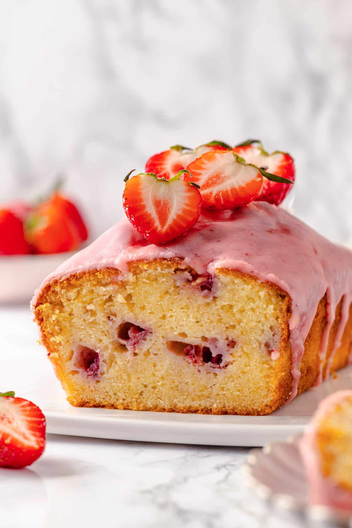 Close-up image, showing the cross-section of strawberry pound cake served on a white plate.